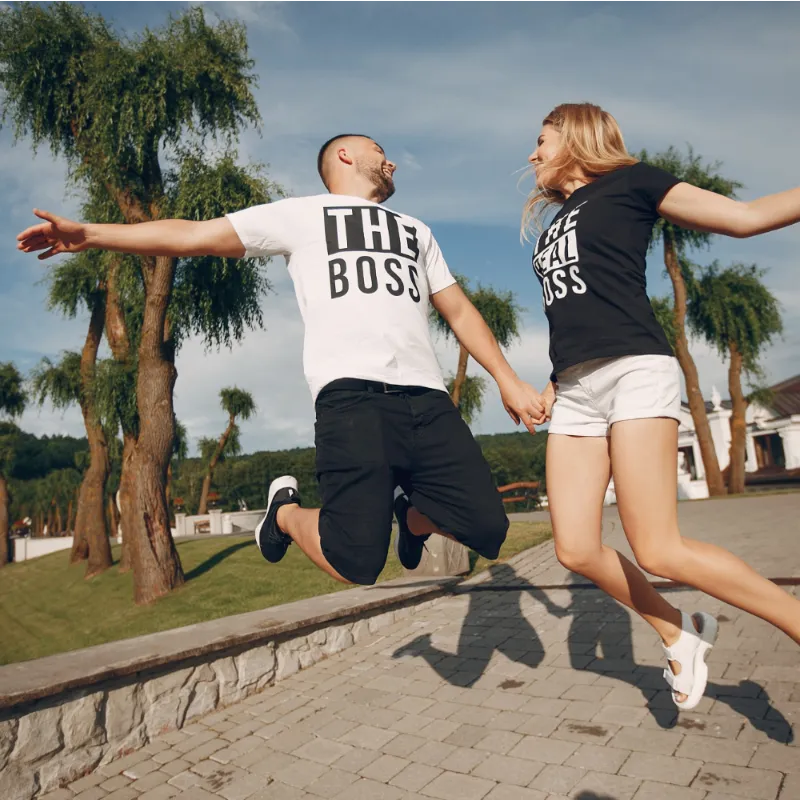 Two people wearing branded T-shirts jumping joyfully, showcasing custom apparel for energetic and positive brand promotion.
