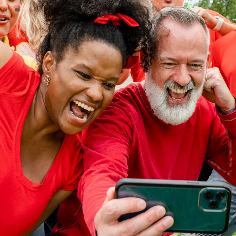 Two people wearing branded T-shirts taking a selfie at an event, capturing a fun and engaging brand experience.